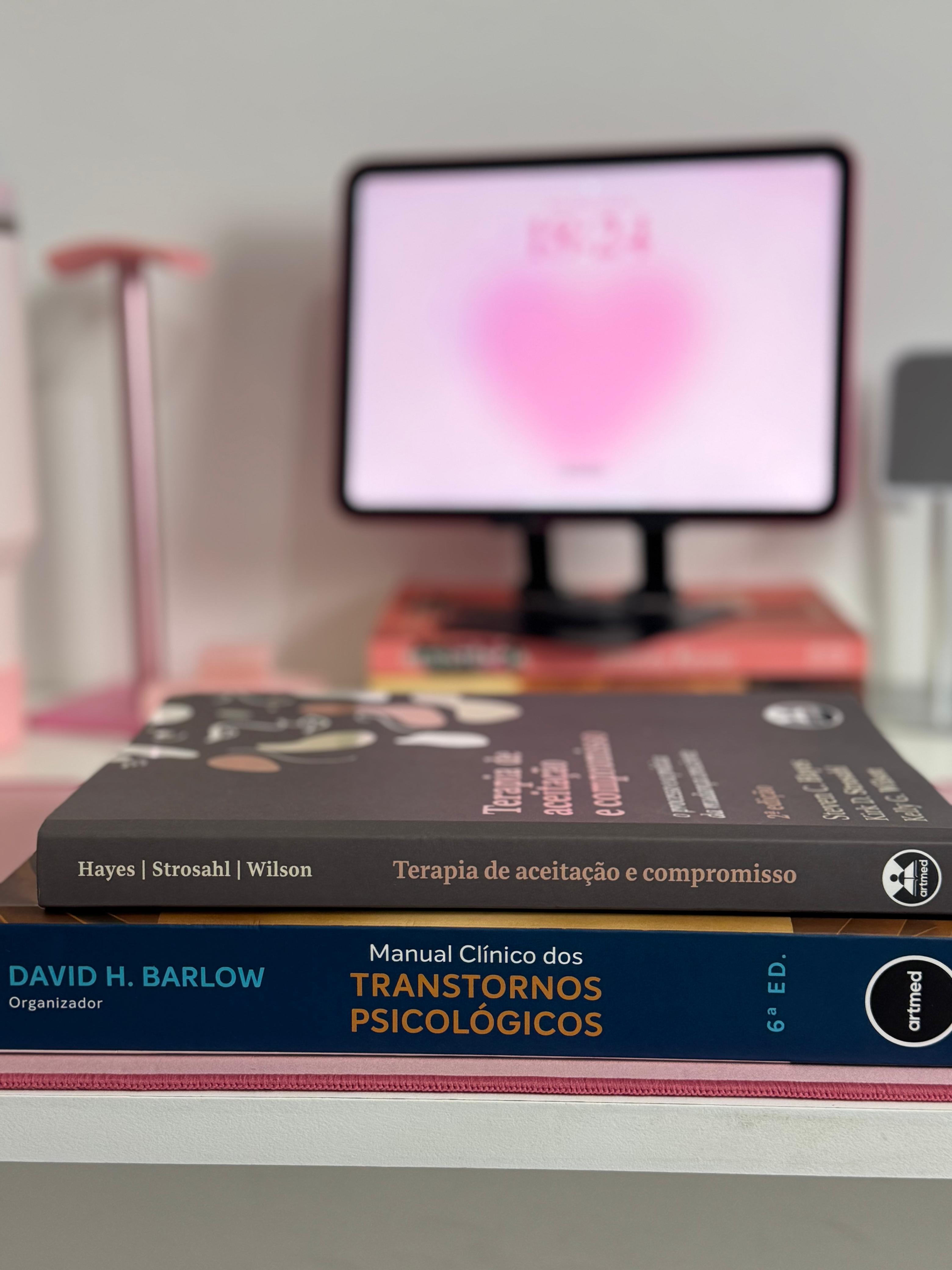 Livros de psicologia sobre a mesa com o tablet ao fundo.