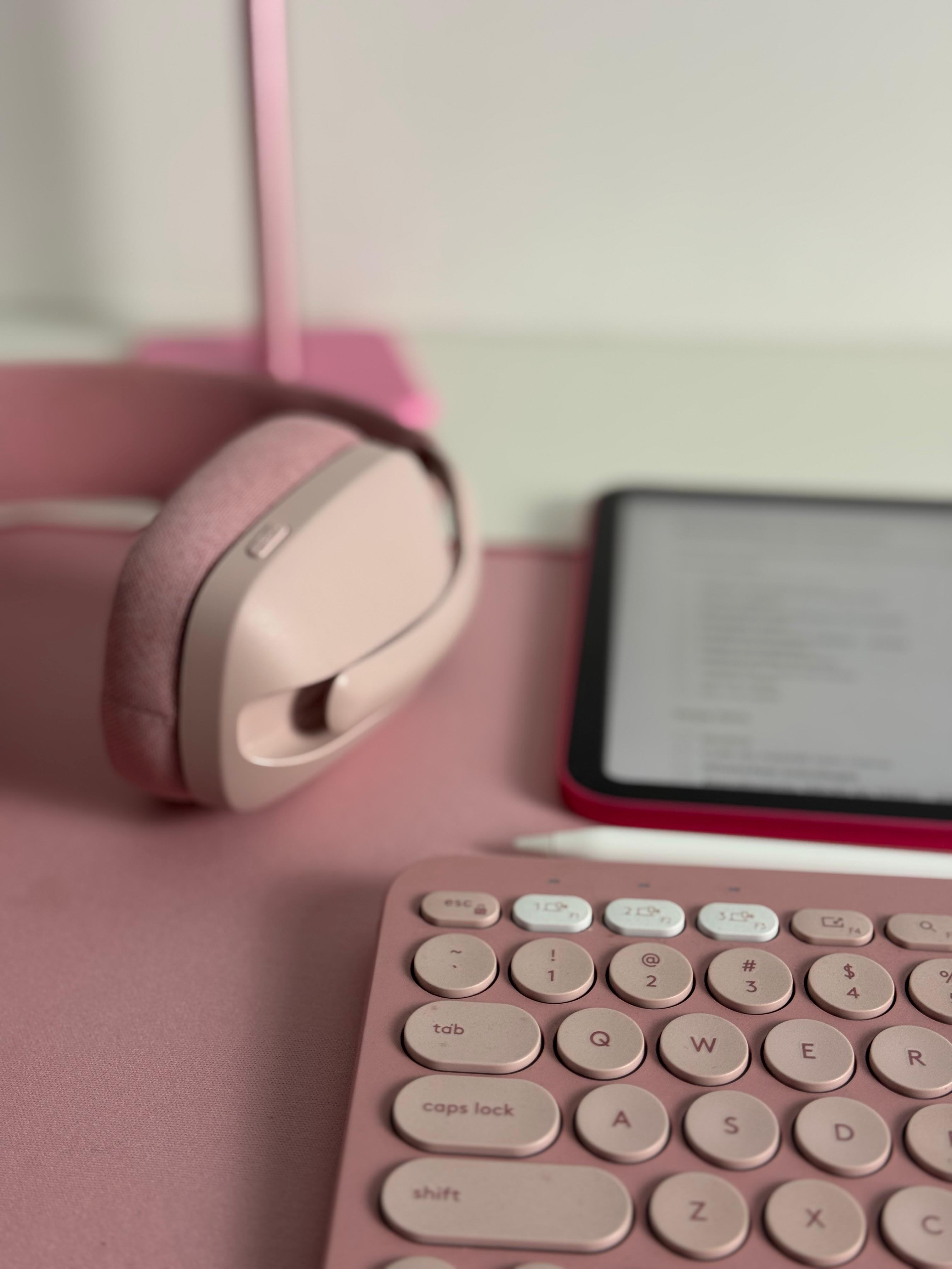 Headphone e teclado em tons de rosa.