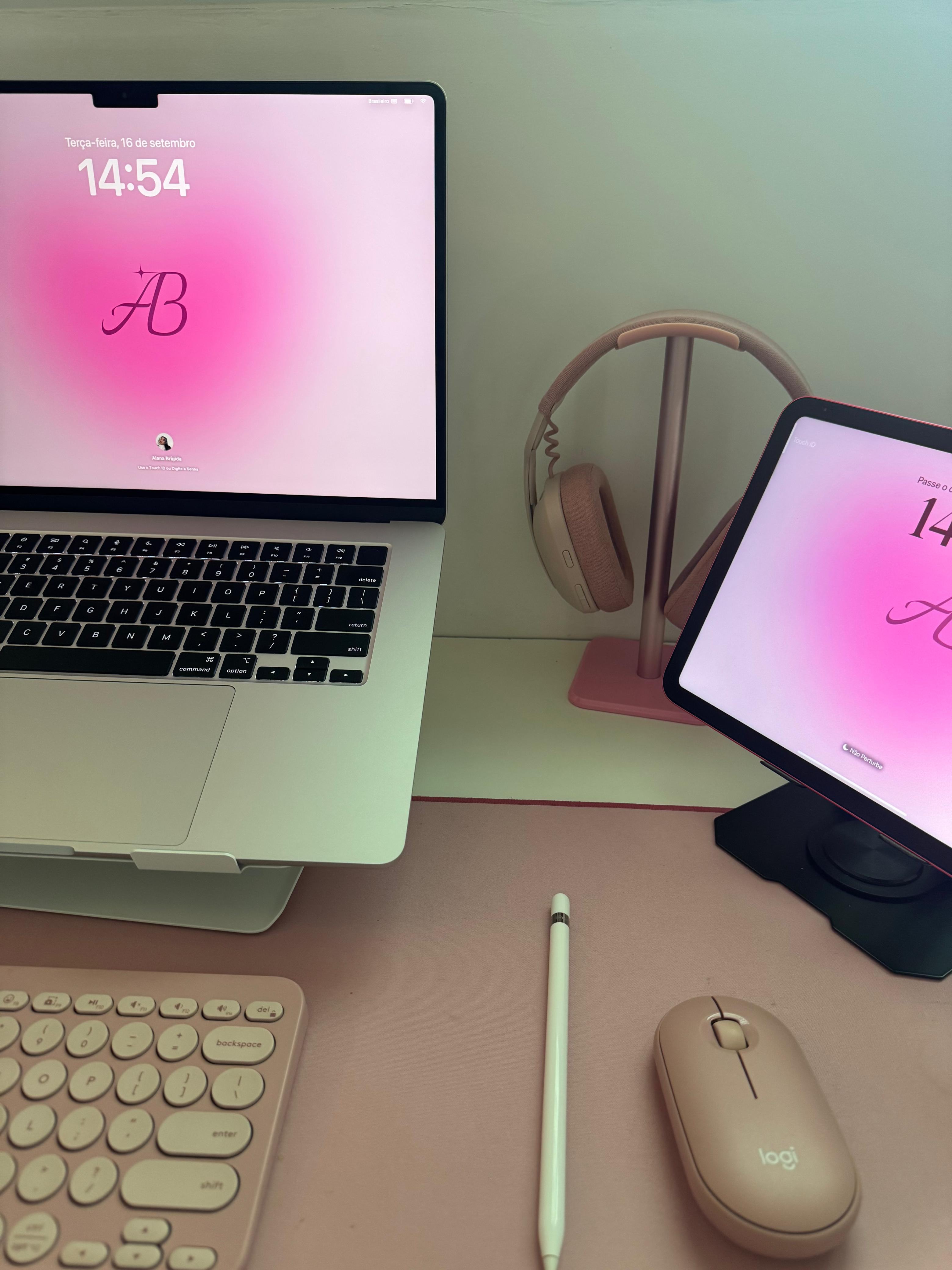 Setup de trabalho com notebook, tablet, mouse e teclado rosa.
